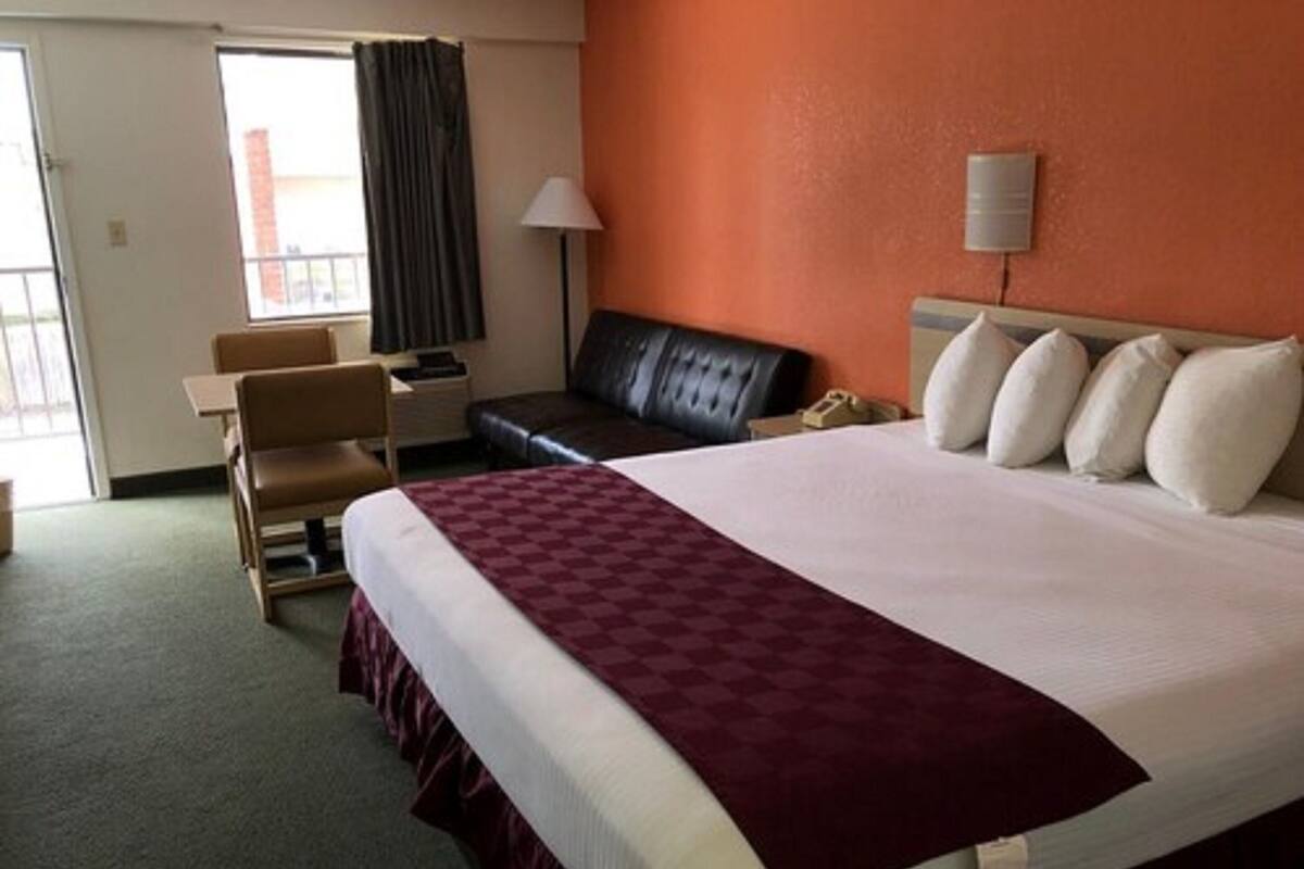 A hotel room with a large bed, a desk, a chair, and a sofa.
