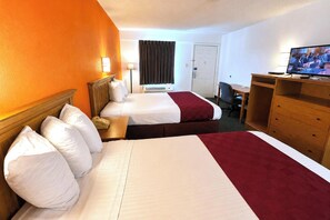 Una habitación de hotel con dos camas, un escritorio, un televisor y una puerta.