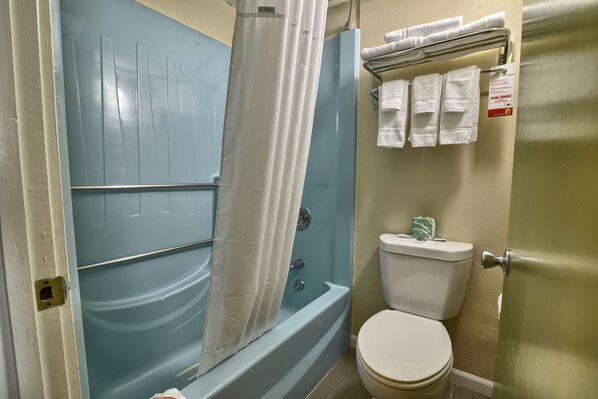Un baño con bañera, inodoro y perchero para toallas.