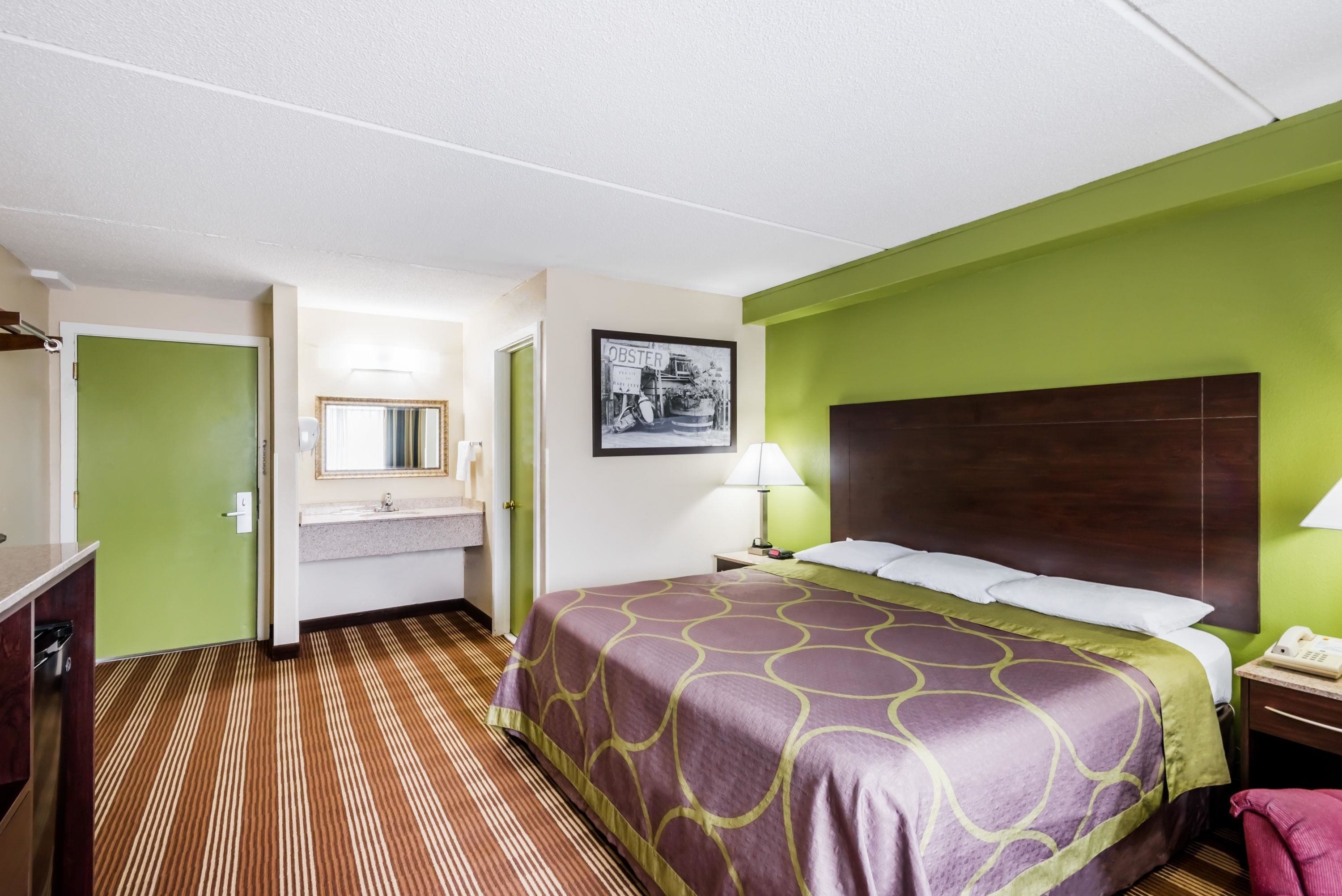A hotel room with a bed, a bathroom, and a green wall.
