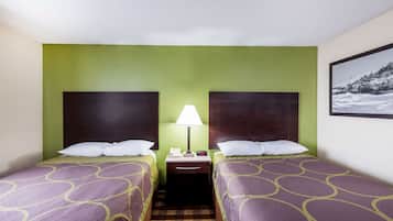 A hotel room with two beds, a nightstand with a lamp, and a framed picture on the wall.