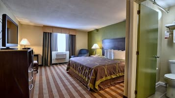 Une chambre d’hôtel comprenant un lit, un bureau avec une lampe, une télévision et une salle de bain.