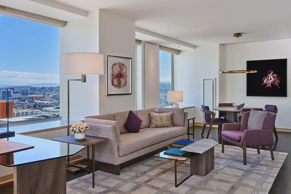 A modern living room with a sofa, armchairs, a coffee table, and a dining area with a table and chairs.