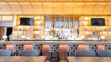 A bar area with a counter, bar stools, and a seating area with tables and chairs.