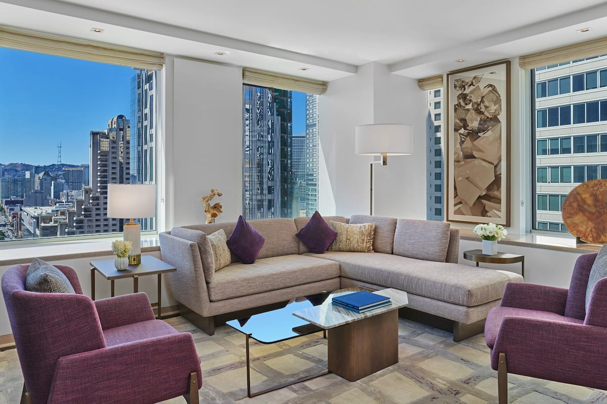 A modern living room with a sectional sofa, two armchairs, a coffee table, and a city view.