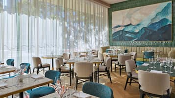 Un restaurant amb diverses taules i caires, i un quadre gran a la paret.