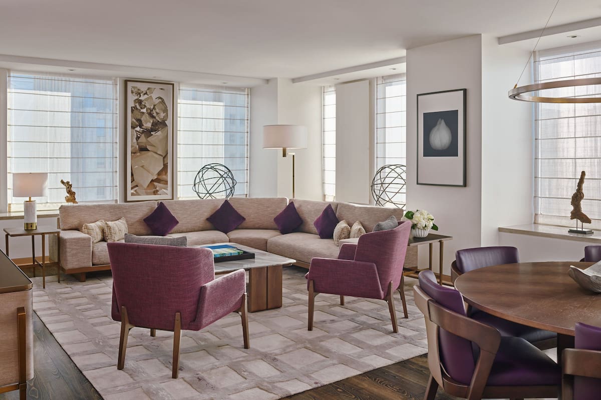 A modern living room with a sofa, chairs, a coffee table, and a dining table.