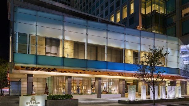 Un hotel moderno con fachada de vidrio, entrada cubierta y un cartel que indica que es un hotel Marriott.
