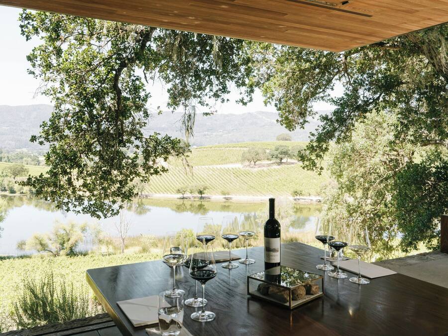 Un espacio de comedor al aire libre con vistas a un viñedo y un lago.
