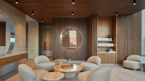 Una moderna zona de recepción con un espejo redondo, asientos y un panel de pared de madera.