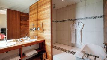 A modern bathroom with a wooden vanity, dual sinks, a large mirror, a shower with a glass door, and a bathtub.