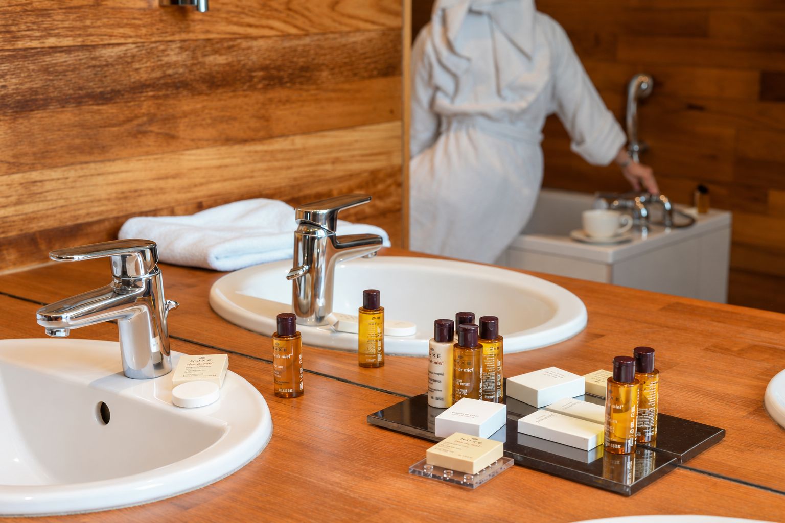 A bathroom with two sinks, a mirror, and various toiletries.