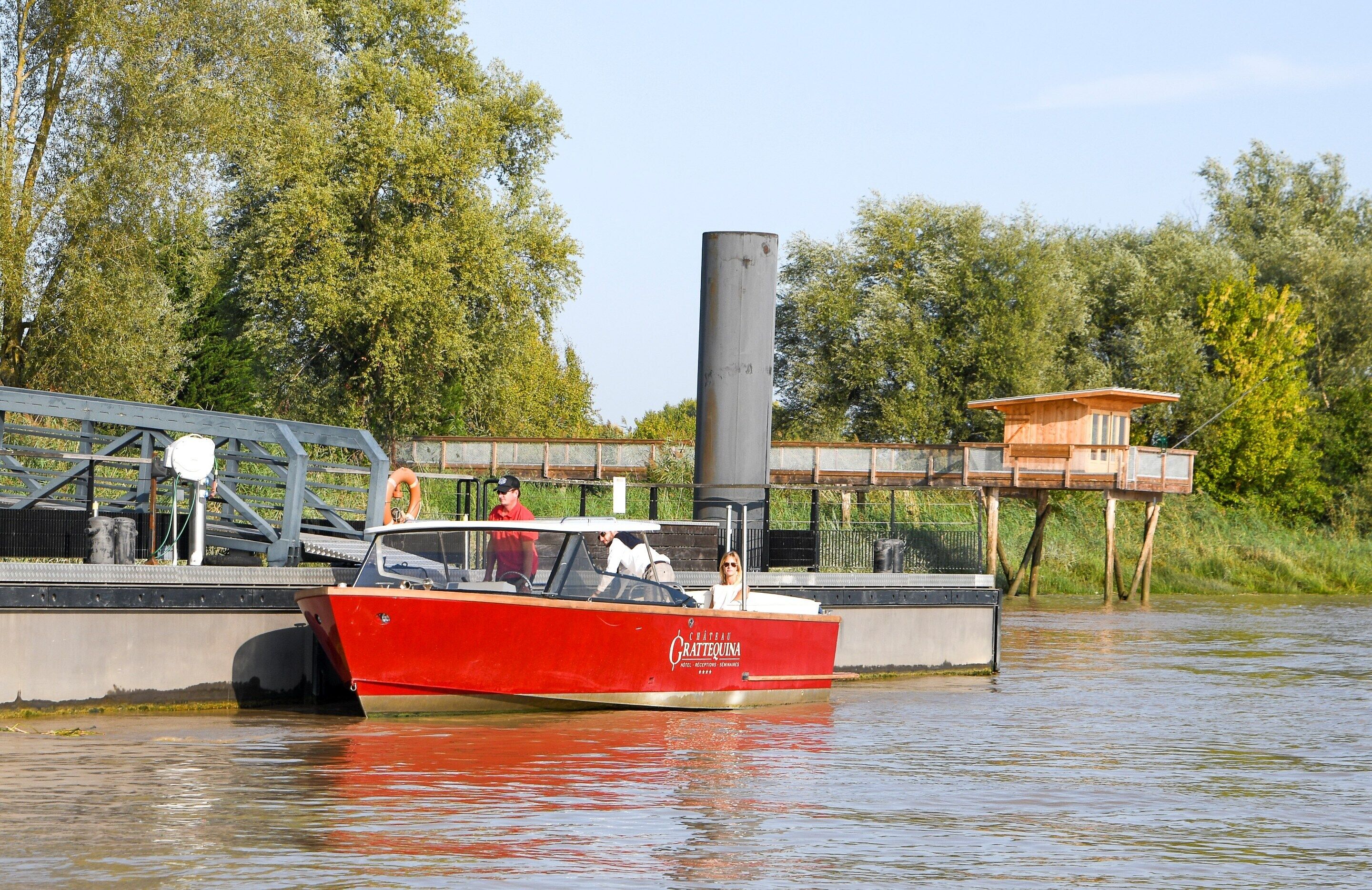 A red boat named 'Cratequina' docked at a pier with a bridge and wooden structures in the background.