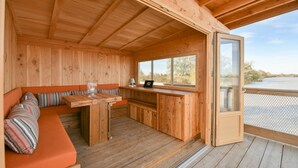 A wooden cabin with a dining area, a bench with cushions, and a large window. - Chateau Grattequina (Blanquefort)