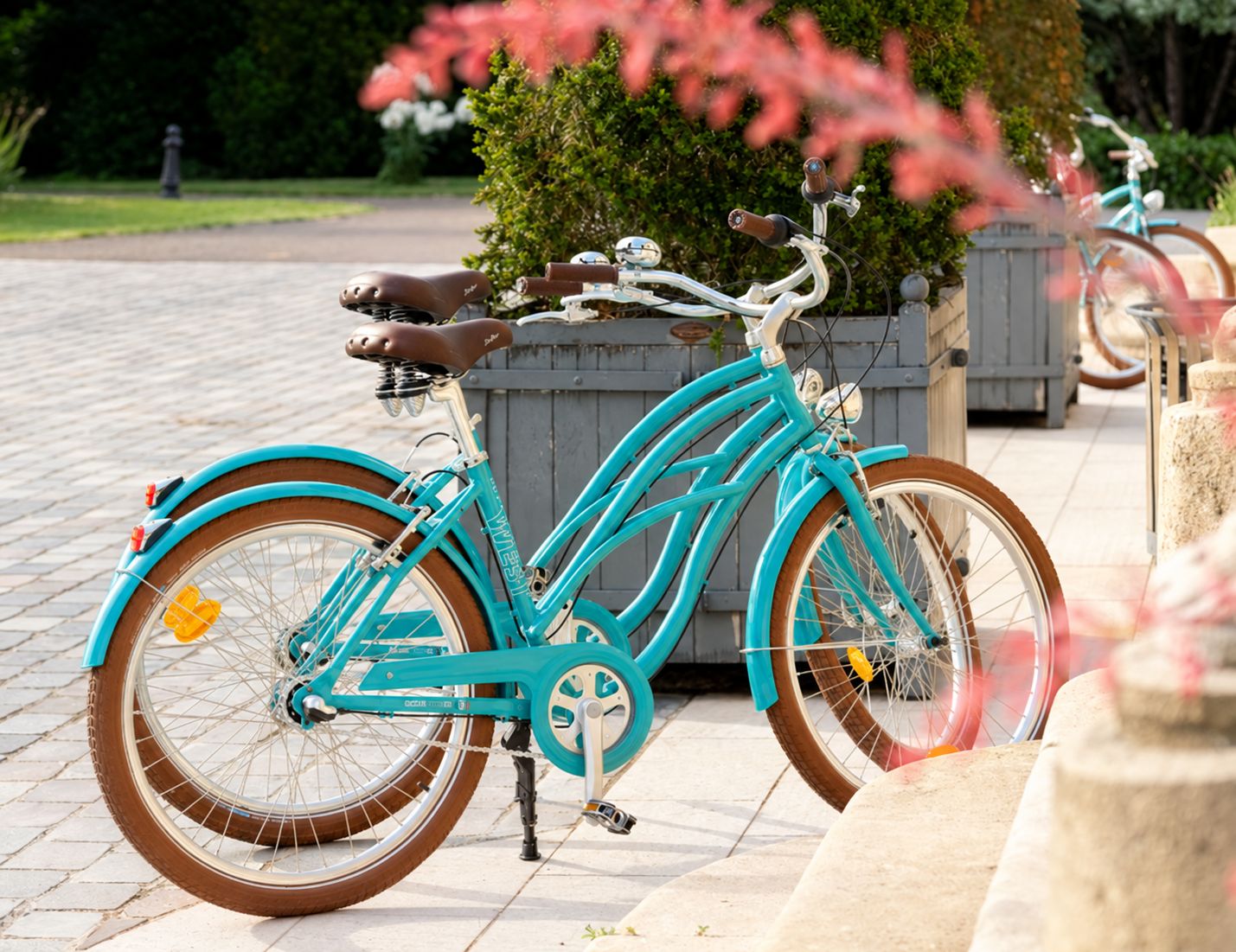 Un vélo turquoise avec une selle en cuir marron, garé sur une surface pavée.