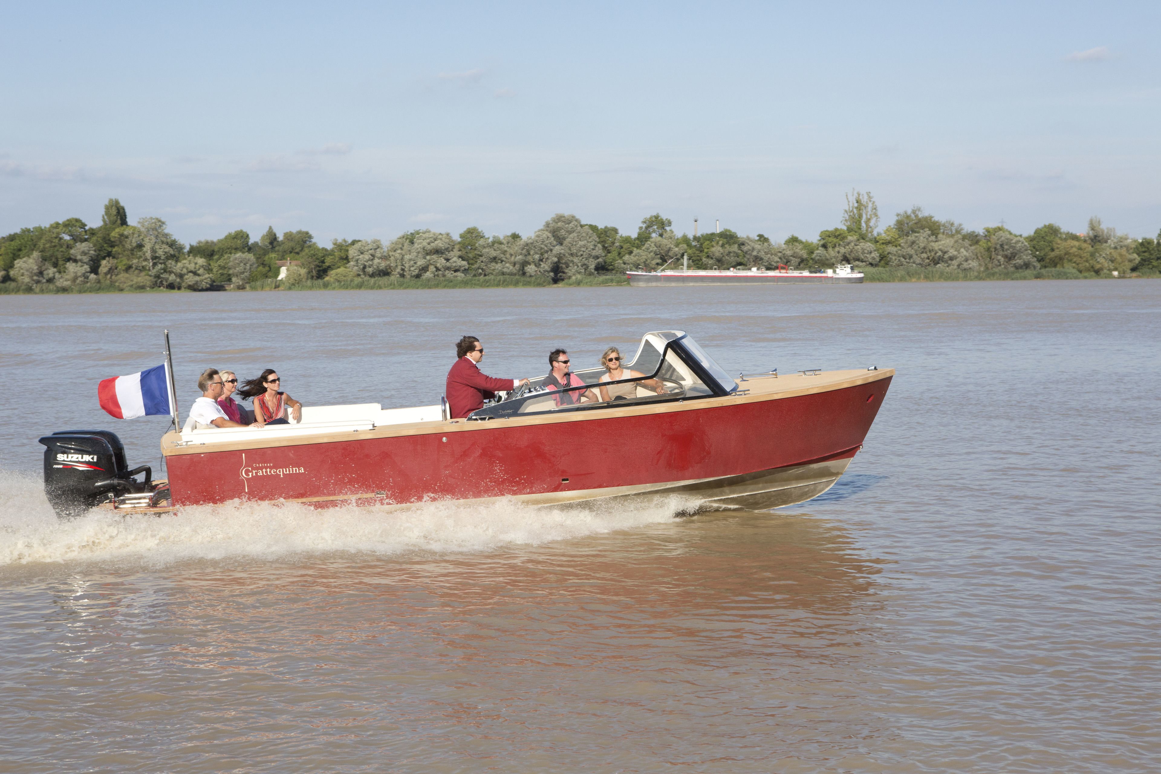 Un bateau rouge transportant des passagers sur une rivière paisible.