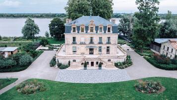 Un grand immeuble à étages, doté d’une façade symétrique, d’une entrée centrale avec des marches et d’un jardin paysager qui l’entoure.