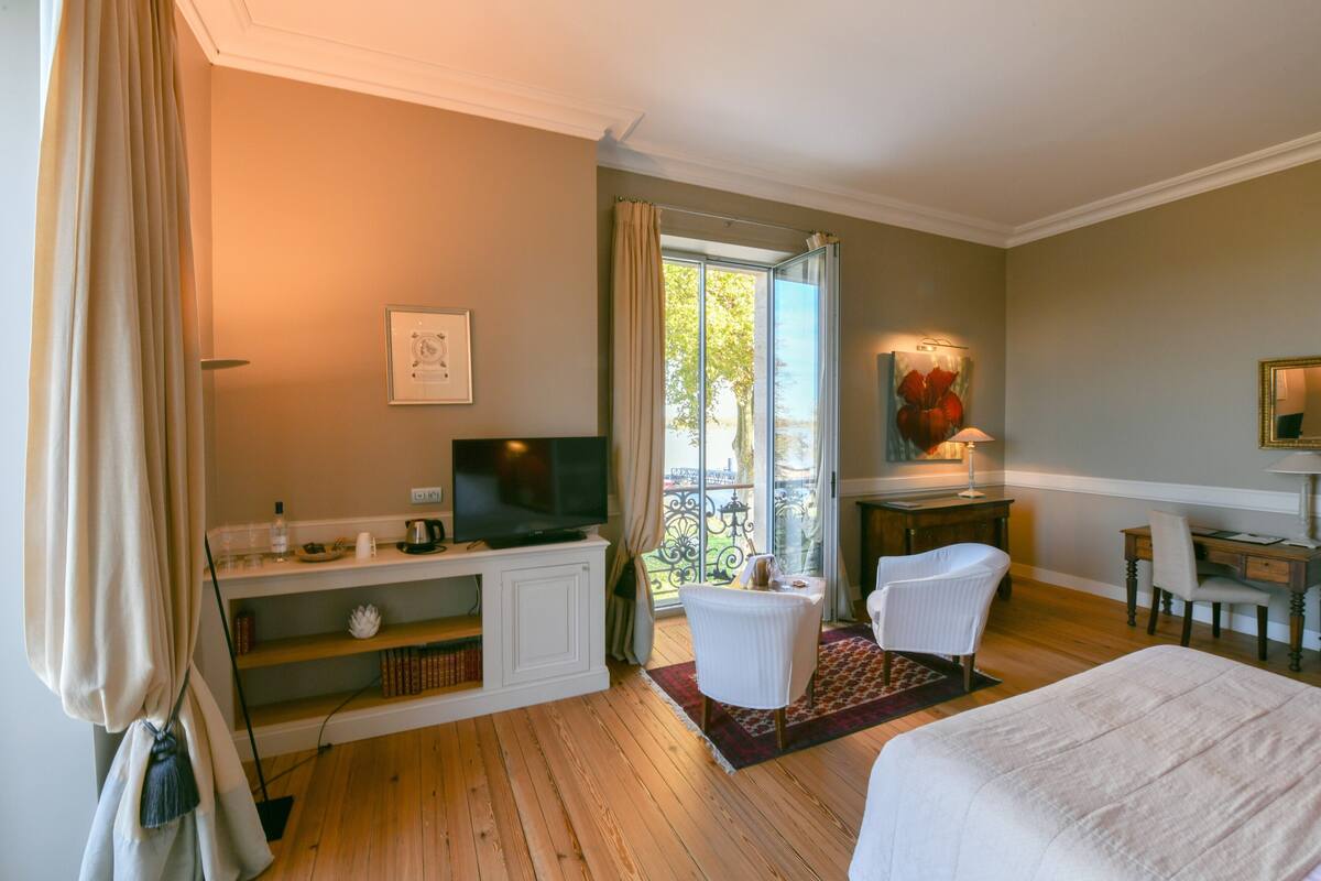 A hotel room with a bed, a desk, a chair, a television, and a view of the outdoors.
