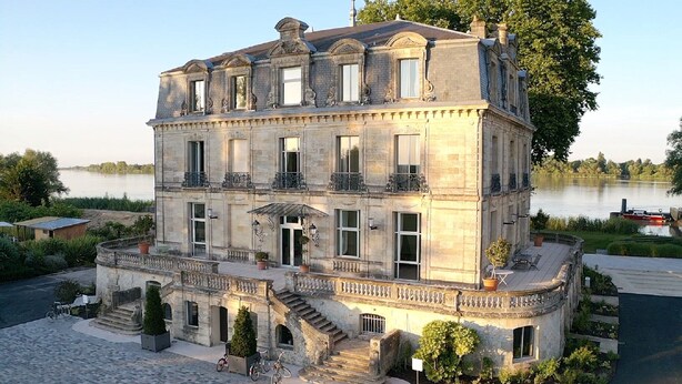 A large, historic stone building with a grand entrance, multiple windows, and a balcony. - Chateau Grattequina (Blanquefort)