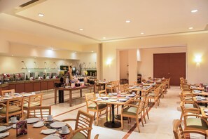 A spacious dining area with multiple tables and chairs, a kitchen area with a coffee station, and a large door in the background. - Fiesta Inn Tijuana Otay (Tijuana)