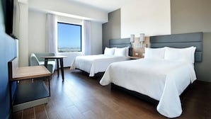A hotel room with two beds, a desk, a chair, and a large window offering a city view. - Fiesta Inn Tijuana Otay (Tijuana)