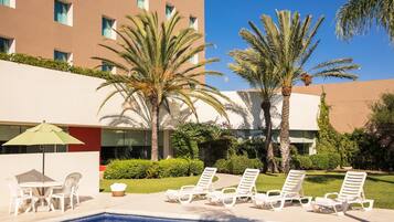 Relax by the pool surrounded by lush greenery and comfortable lounge seating.