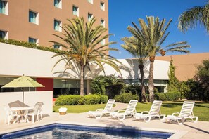 A pool area with lounge chairs, a table with chairs, and a palm tree. - Fiesta Inn Tijuana Otay (Tijuana)