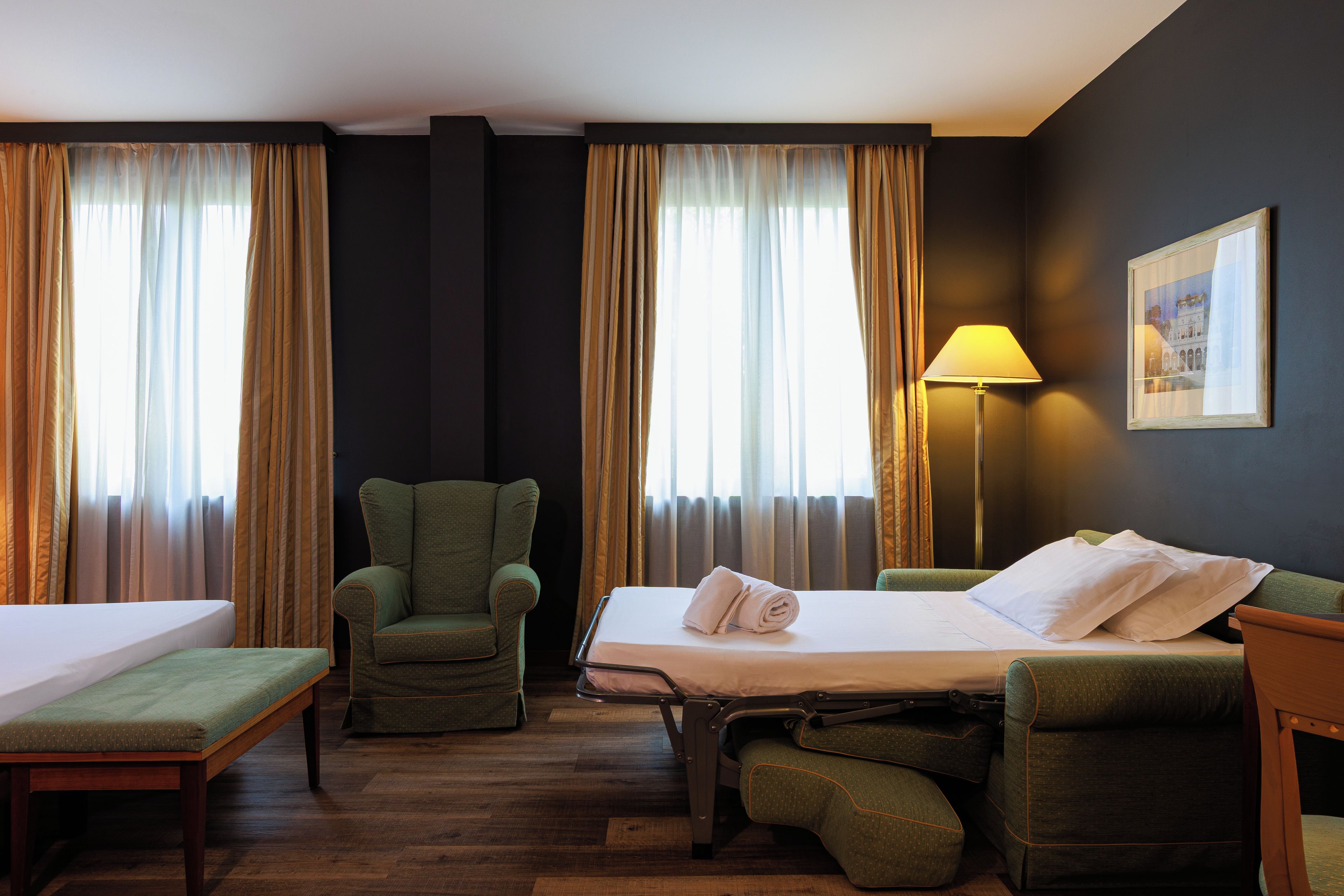 Ein Hotelzimmer mit einem Bett, einem Stuhl, einem Schreibtisch und einer Lampe.