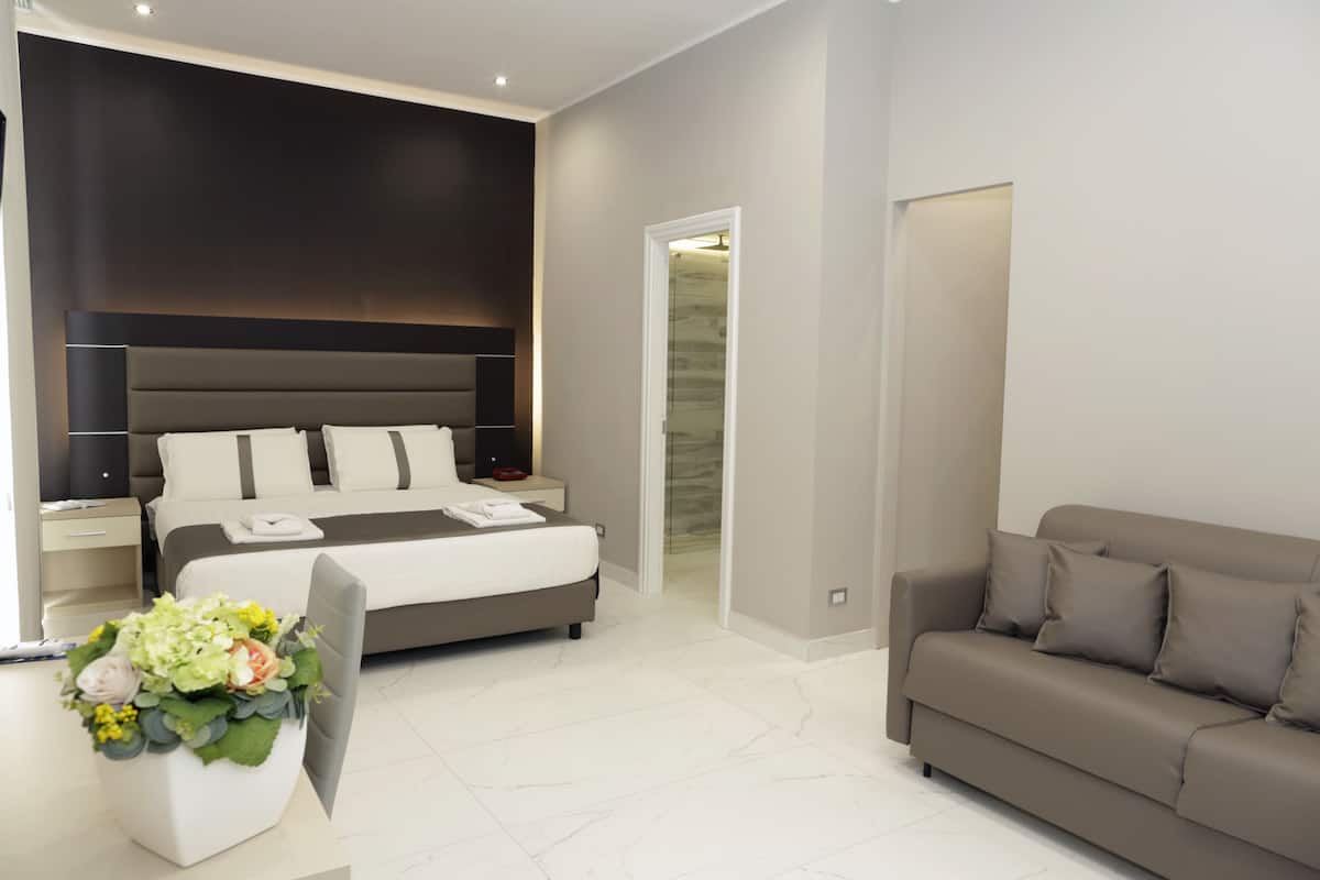 A modern bedroom with a large bed, bedside tables, a sofa, and a decorative vase.