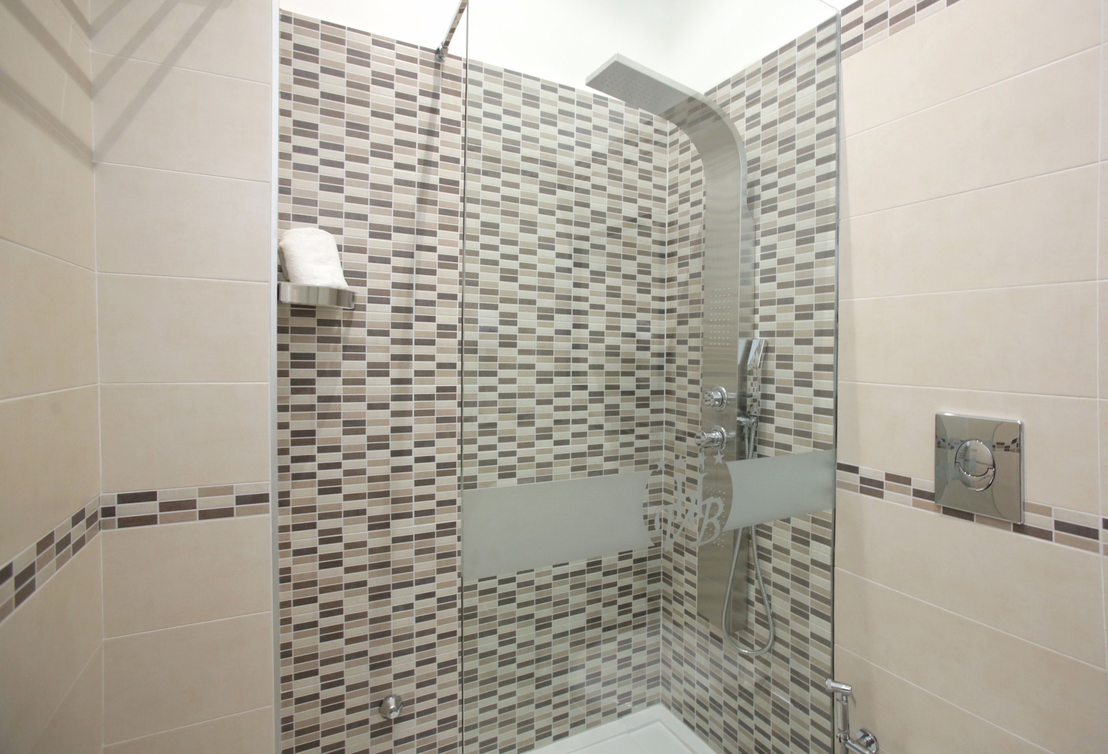 Ducha con pared de azulejos, puerta de vidrio y panel de control.