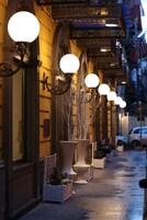 Une rue bordée de grands jardinières et d’élégants lampadaires, ce qui évoque un quartier urbain historique ou huppé.