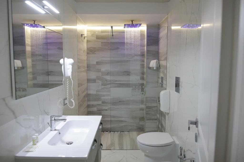 Une salle de bain moderne avec une douche à parois de verre, un lavabo blanc et des toilettes.