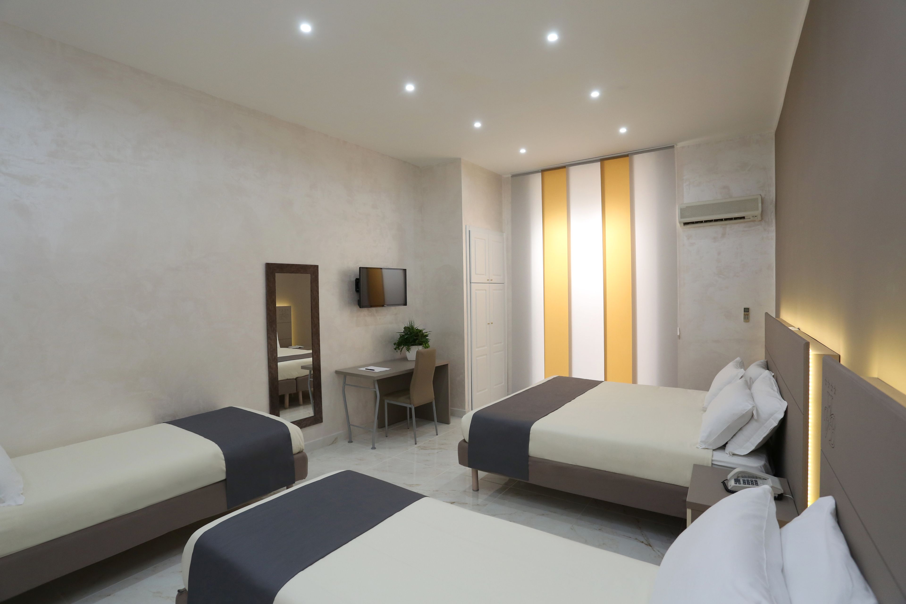 Habitación de hotel con dos camas, un escritorio, una silla, un televisor y un equipo de aire acondicionado.