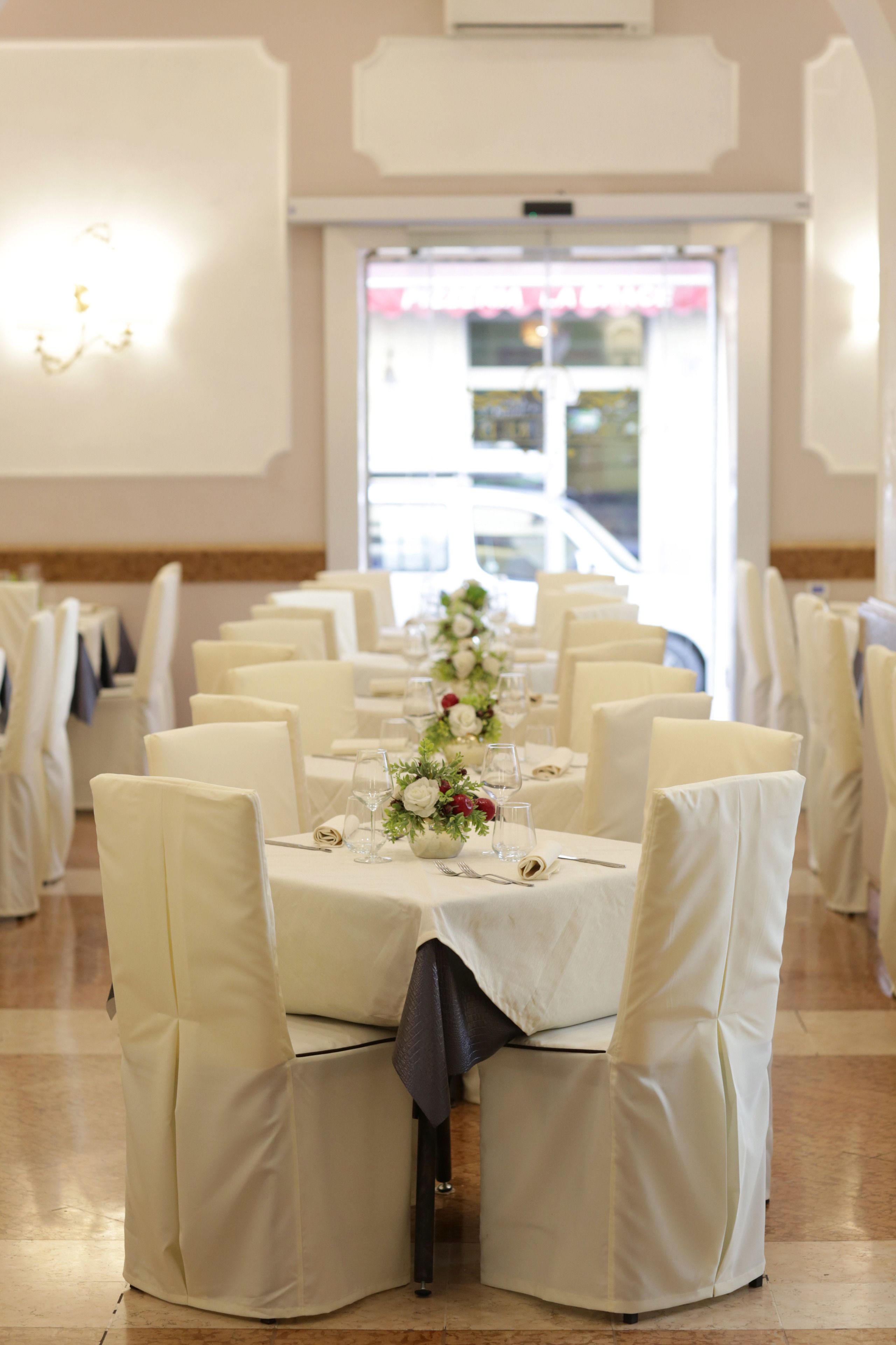 Un espace repas avec des nappes blanches, des chaises et une composition florale en guise de centre de table.