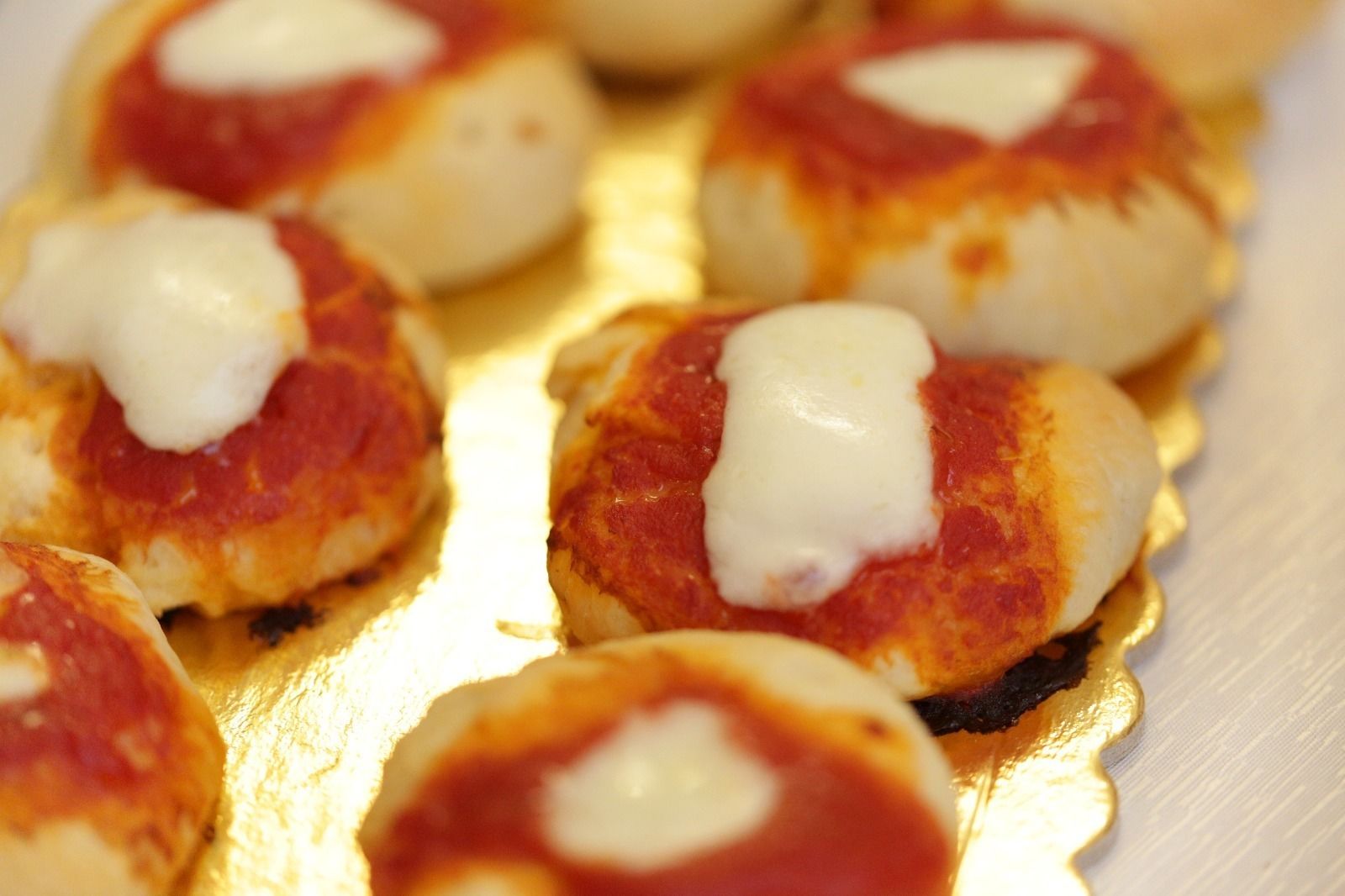 Un vassoio con piccoli bocconcini rotondi, cotti e guarniti con salsa bianca, probabilmente un antipasto o uno spuntino.