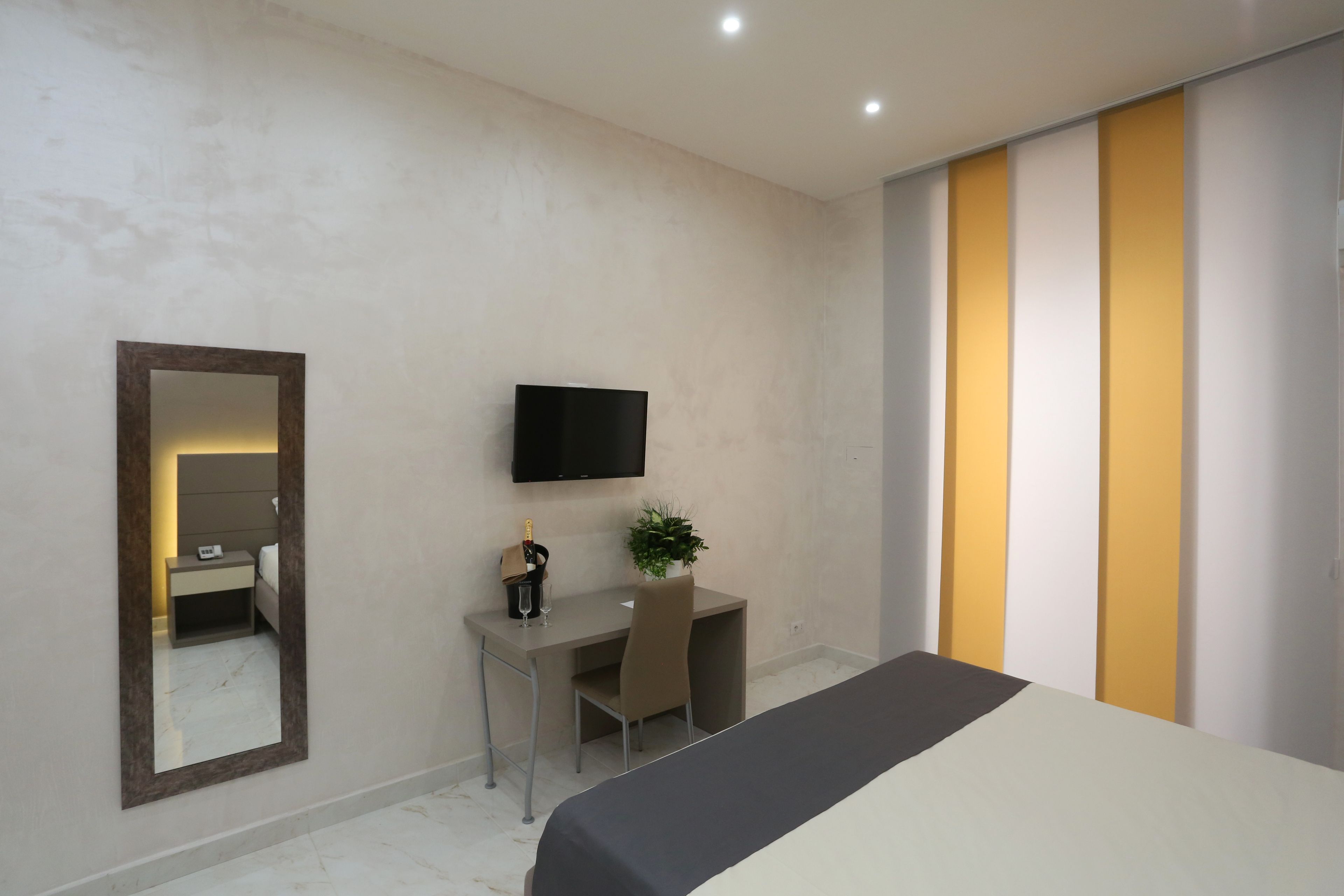 Une chambre d’hôtel moderne avec un grand lit, un bureau avec une chaise, une télévision et un miroir.