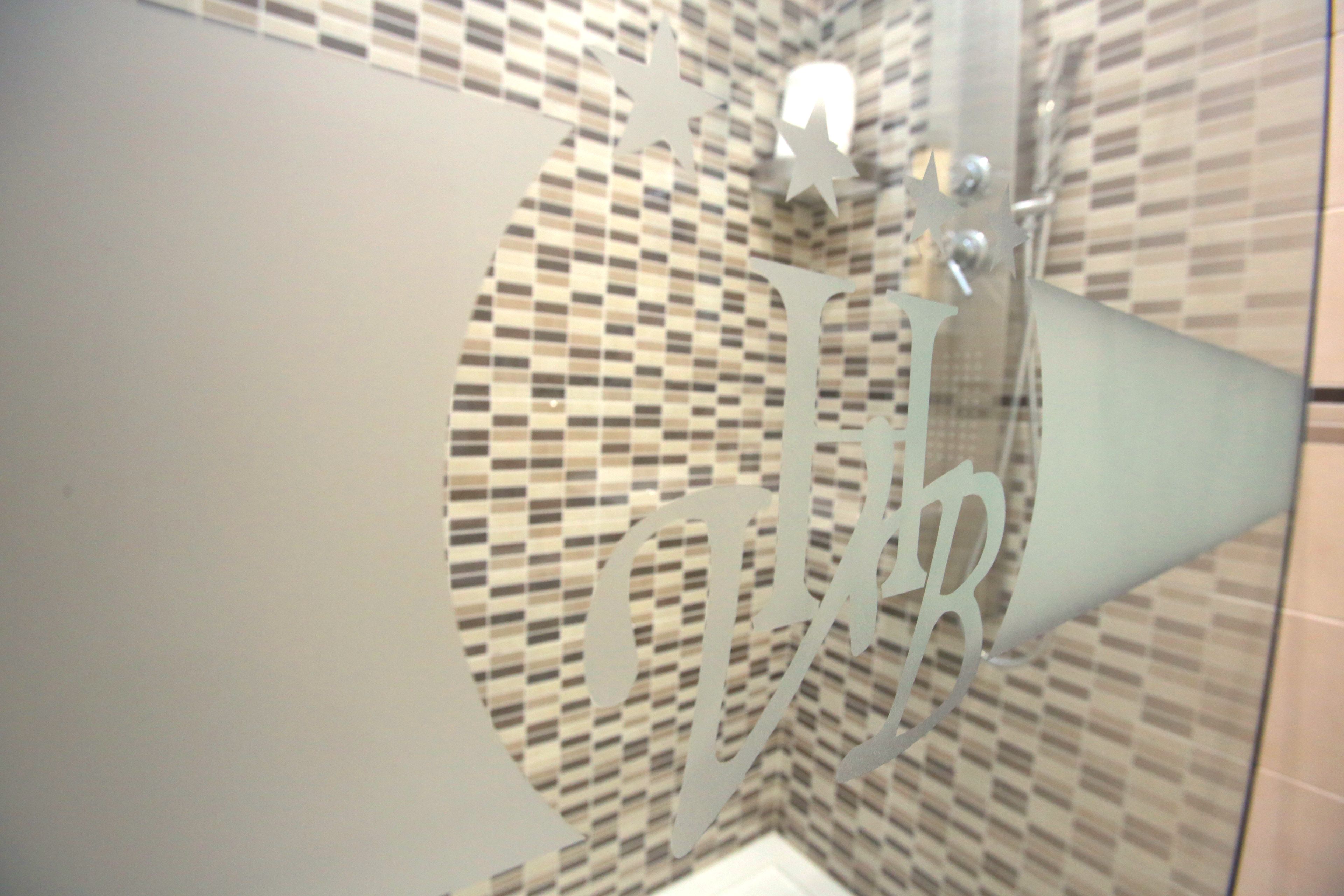 A bathroom with a checkered tile backsplash and a large, metallic, star-shaped mirror.