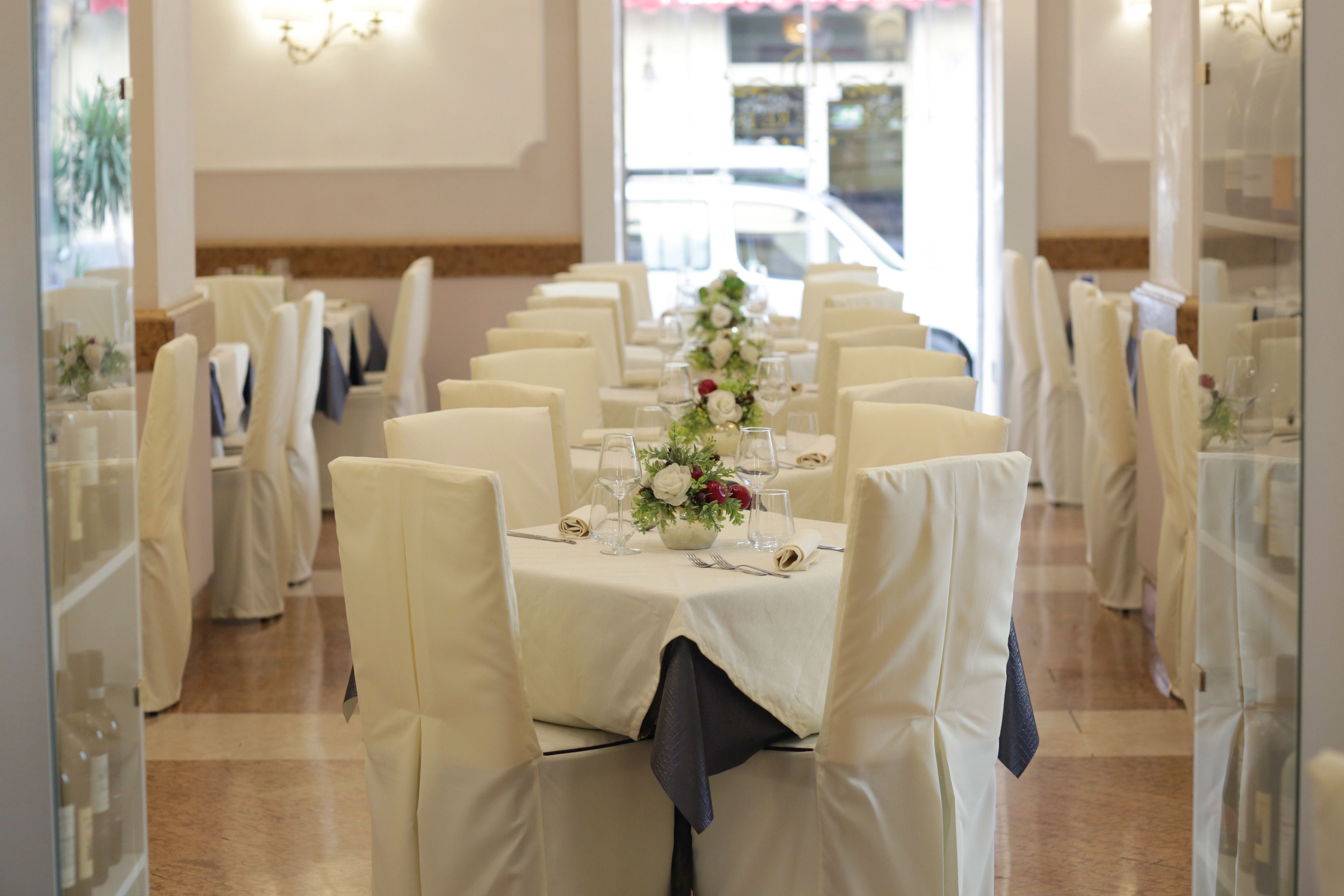 Una larga mesa de comedor con manteles blancos y sillas, preparada para un evento formal.