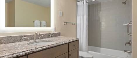 A bathroom with a double sink vanity, a toilet, and a walk-in shower with a glass door.