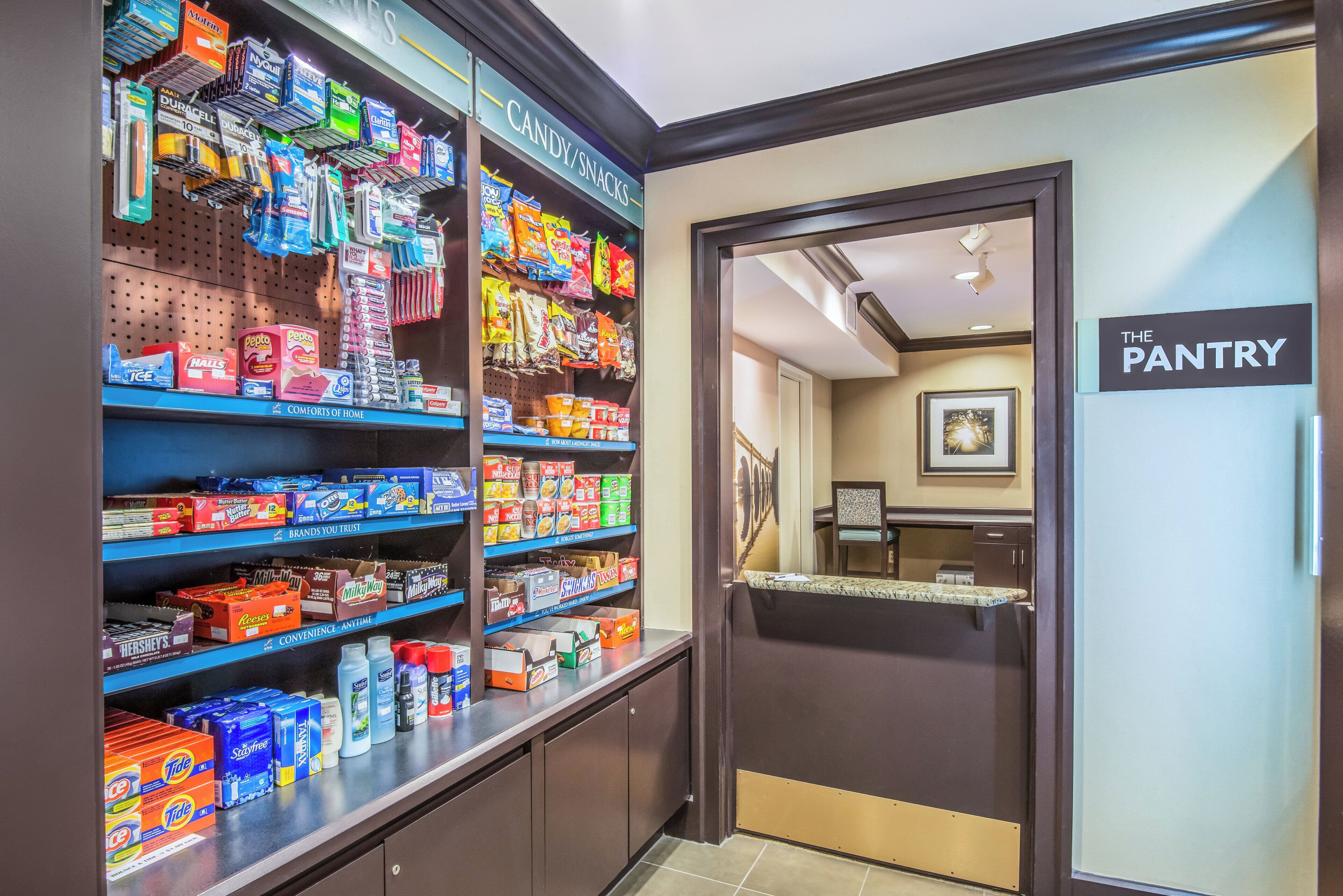 Un garde-manger d’hôtel avec des étagères remplies de collations et de produits de toilette.