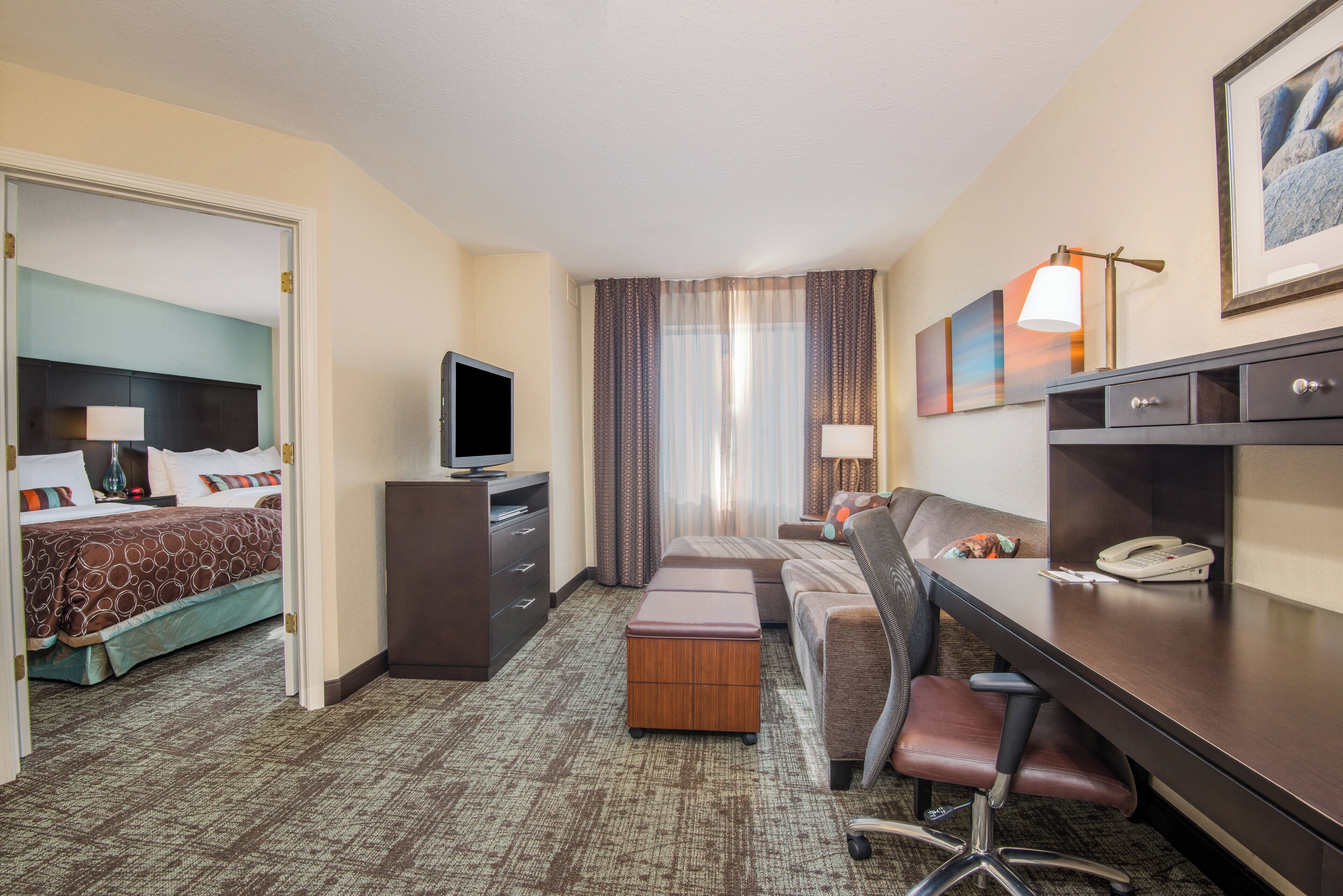 Una habitación de hotel con una cama, un escritorio, una silla, un televisor y un teléfono.