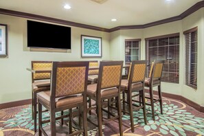 A dining area with a large table, chairs, a flat-screen TV, and artwork on the walls. - Staybridge Suites Allentown West by IHG (Allentown)
