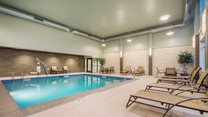 An indoor swimming pool with lounge chairs and a tiled floor.
