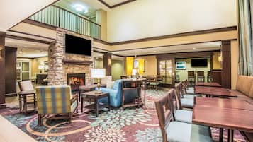 A spacious lobby with a stone fireplace, comfortable seating, and a high ceiling.