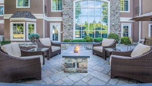 A patio area with wicker furniture and a stone fire pit.