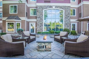 A patio area with wicker furniture and a stone fire pit.