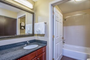 A bathroom with a sink, mirror, and white bathtub. - Staybridge Suites Allentown West by IHG (Allentown)