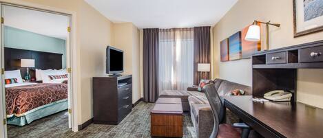 Una habitación de hotel con cama, escritorio, silla, televisor y teléfono.