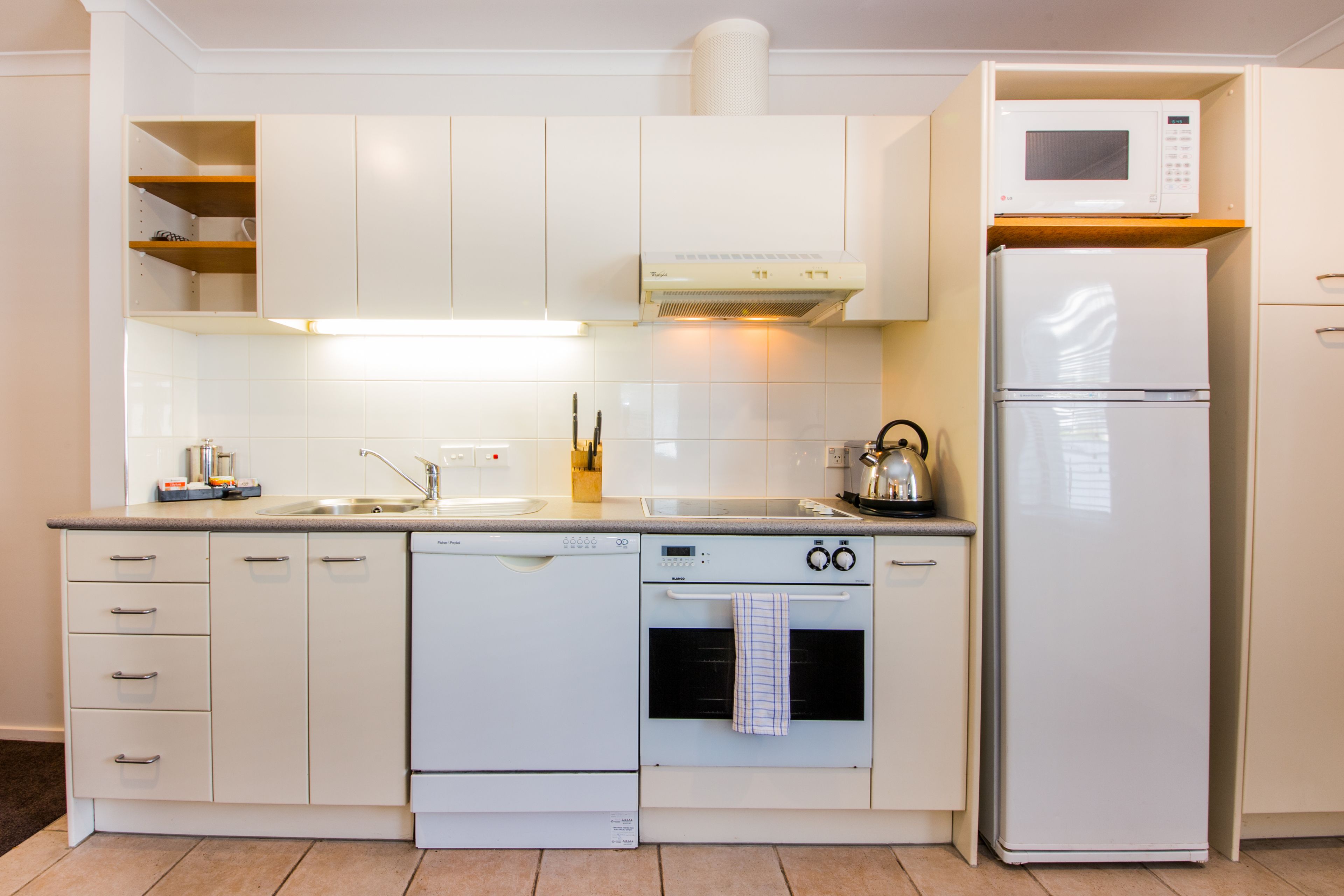 A modern kitchen with white cabinetry, a built-in oven, a microwave, and a dishwasher.