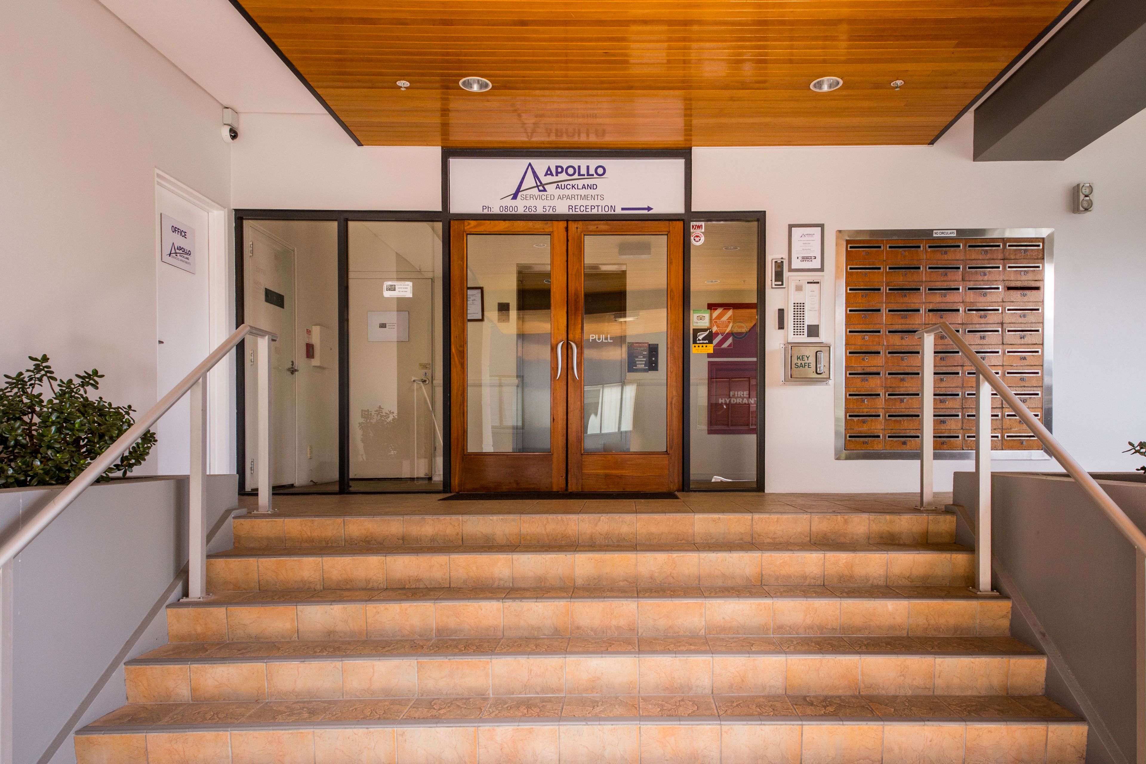 A reception area with a wooden ceiling, a reception desk, and a staircase leading to the upper floors.